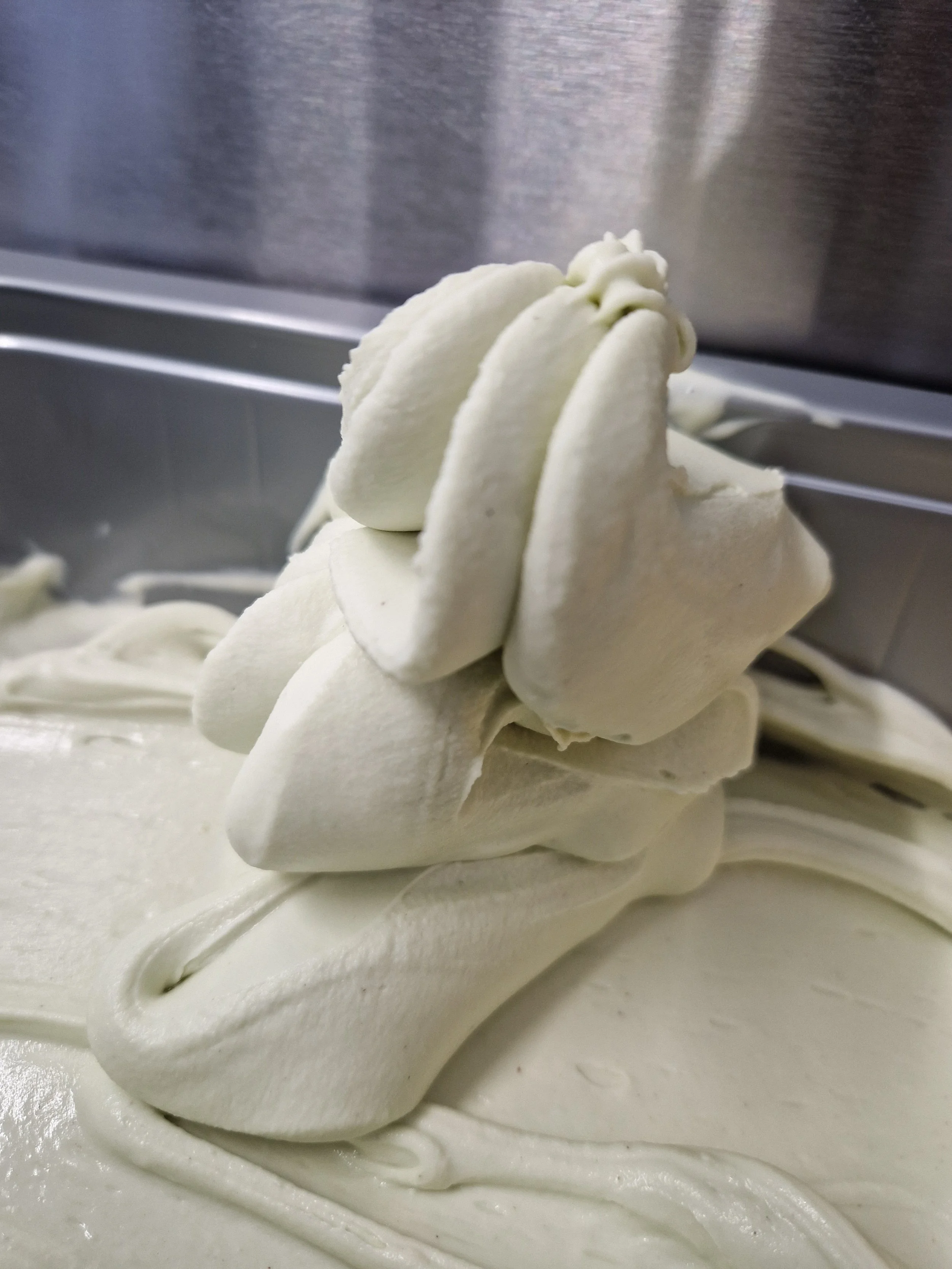Kunststoff, auf dem sich cremiges, weißes Material befindet, wahrscheinlich Eismasse, in einem Kühlraum oder Gefrierschrank.