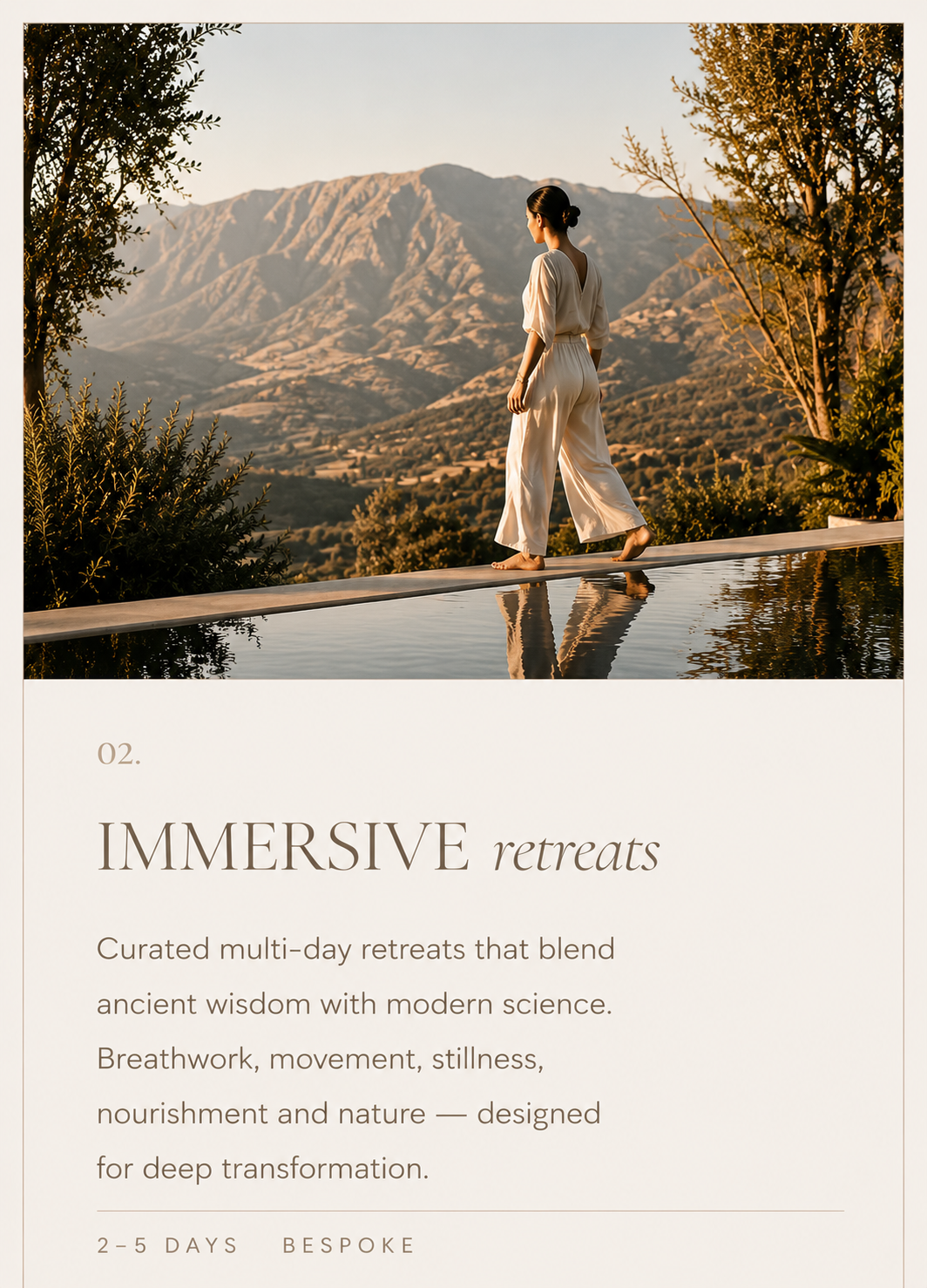 A woman in white clothing walking barefoot on a narrow path beside a reflecting pool, with mountains and trees in the background, during sunset.