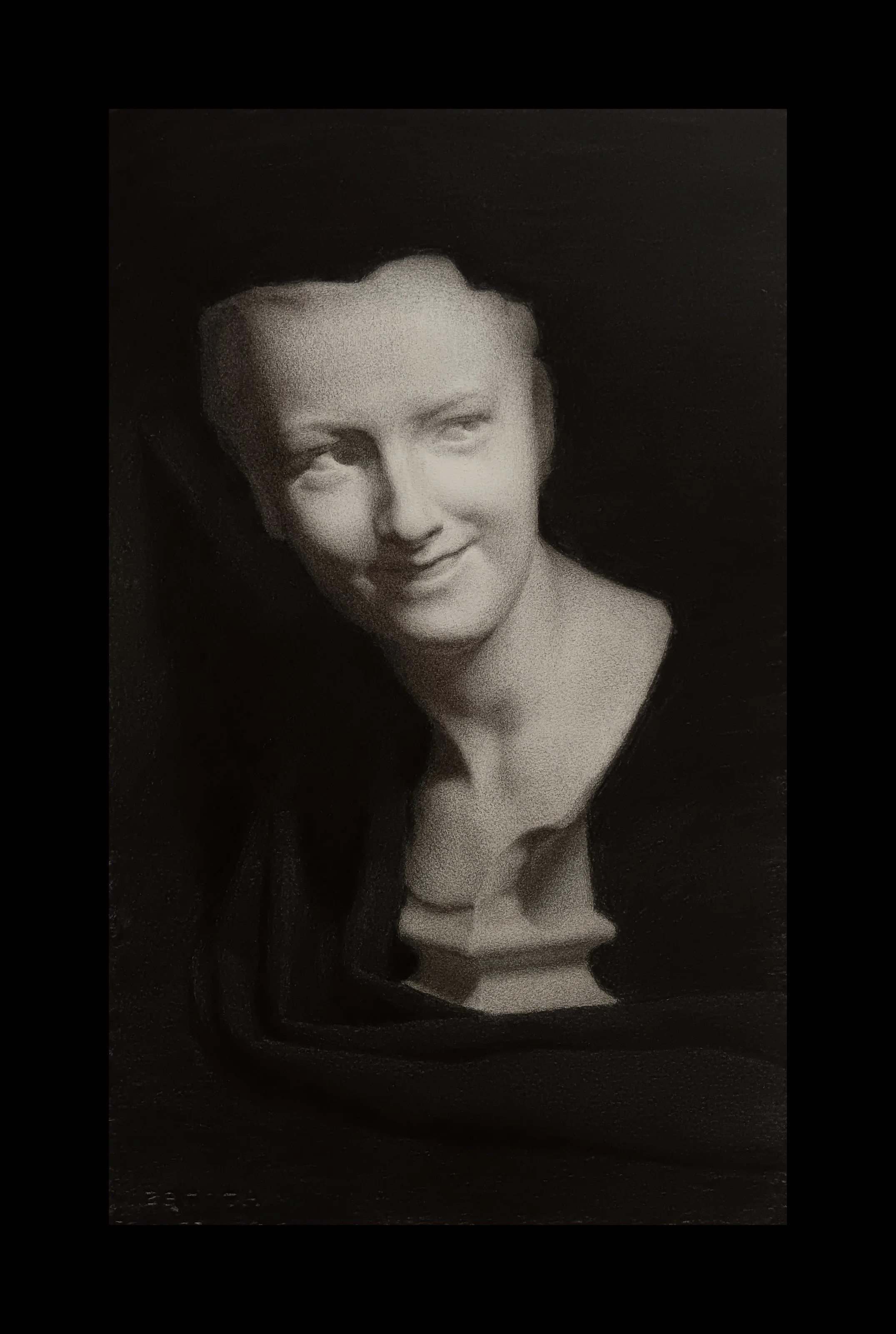 Black and white portrait of a little boy with a soft smile, looking slightly to the side against a dark background.