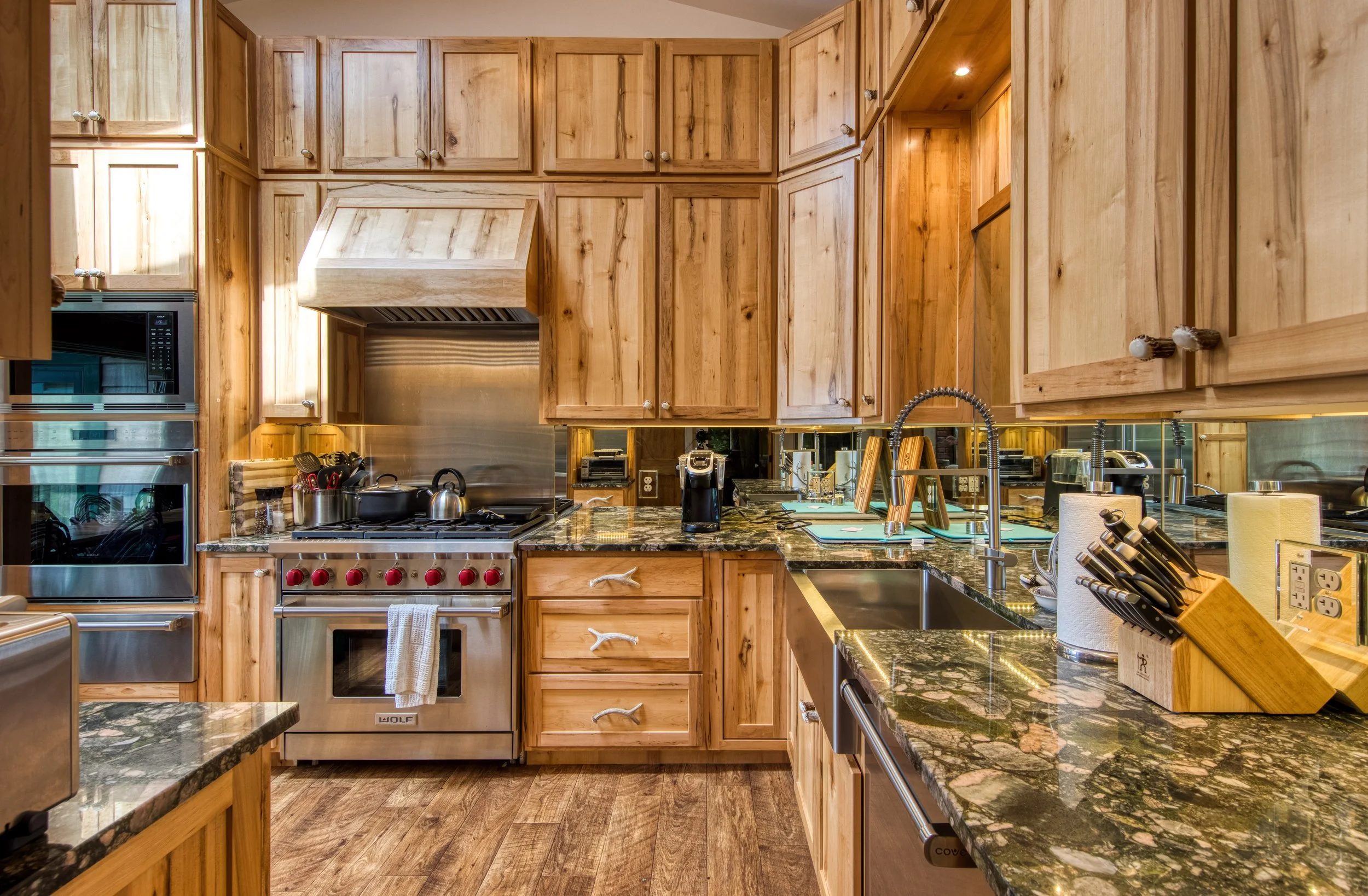 Kitchen with wooden cabinets, granite countertops, and stainless steel appliances, including a stove, microwave, and double oven.