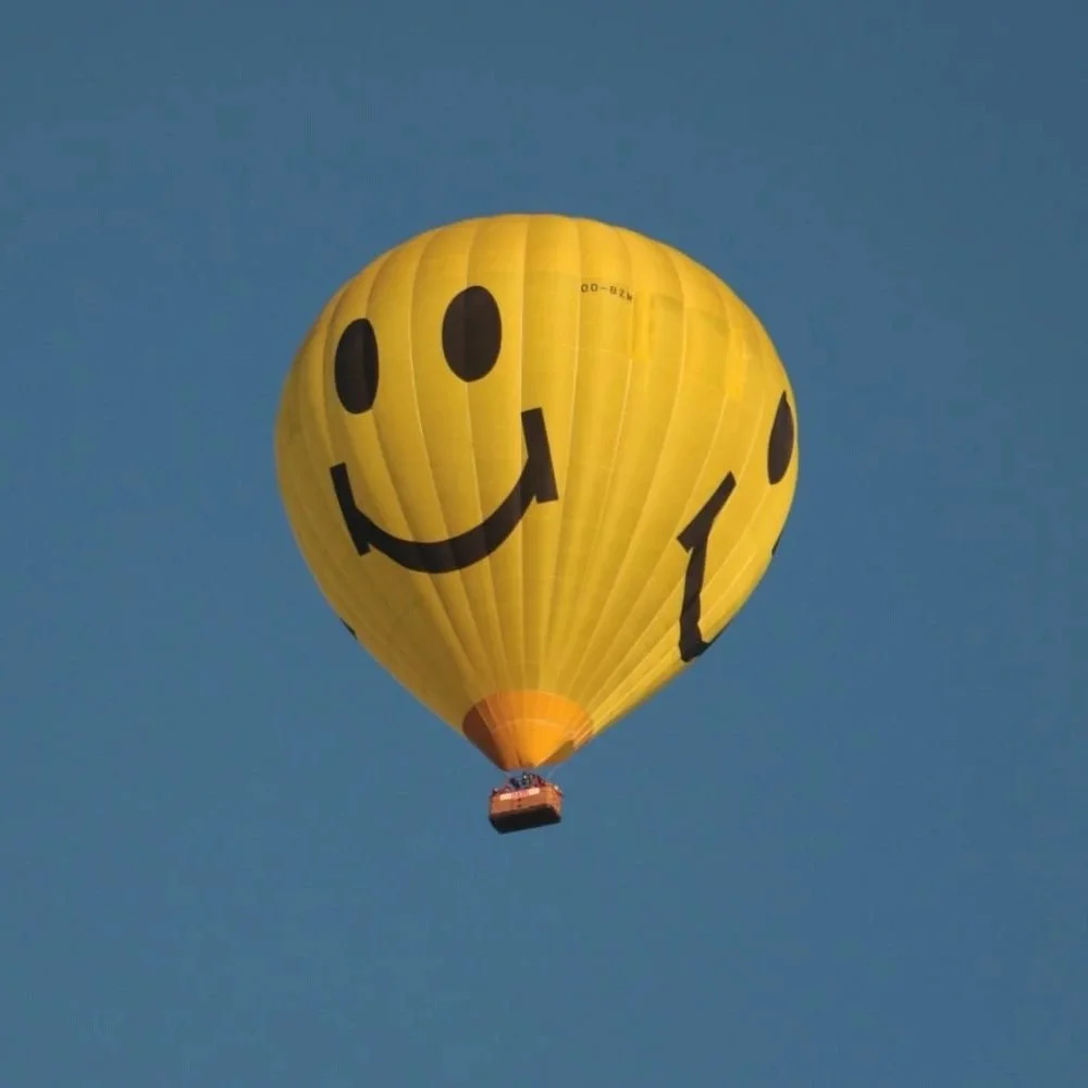 A yellow hot air balloon with a smiley face.