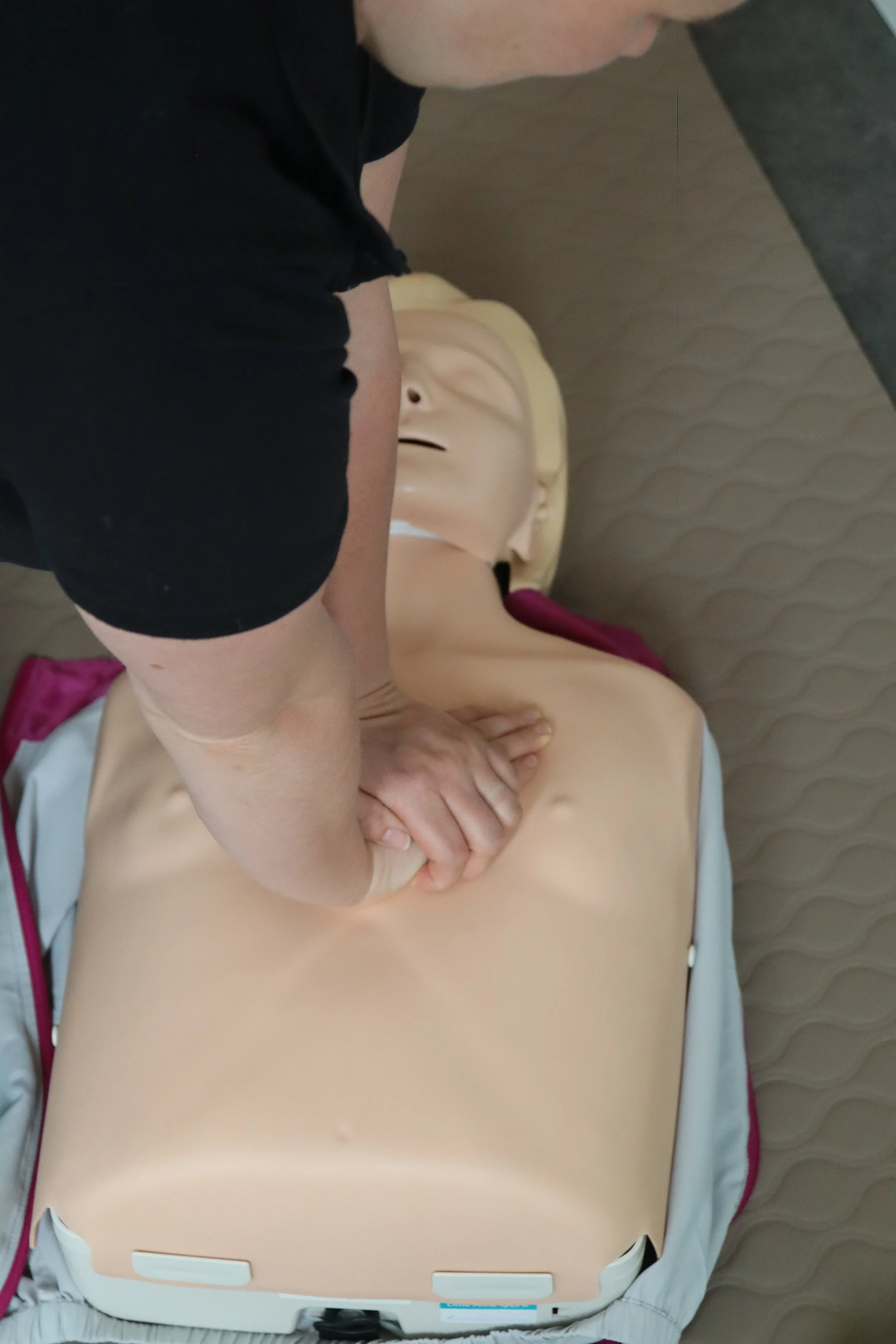 Person führt eine Herz-Lungen-Wiederbelebung an einer Übungspuppe durch.