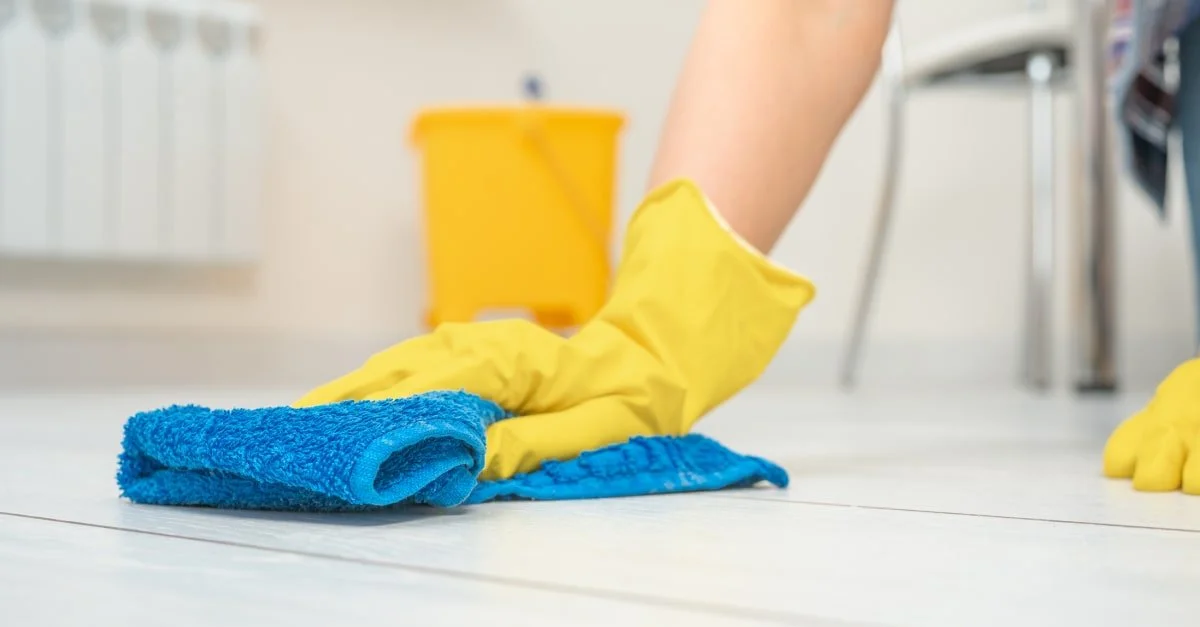 een-persoon-met-handschoenen-maakt-de-vloer-schoon.jpg