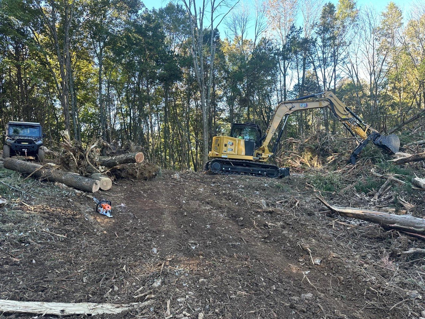 Clearing timber and brush to open this lot up. Chainsaw does the cutting, the machine does the moving.