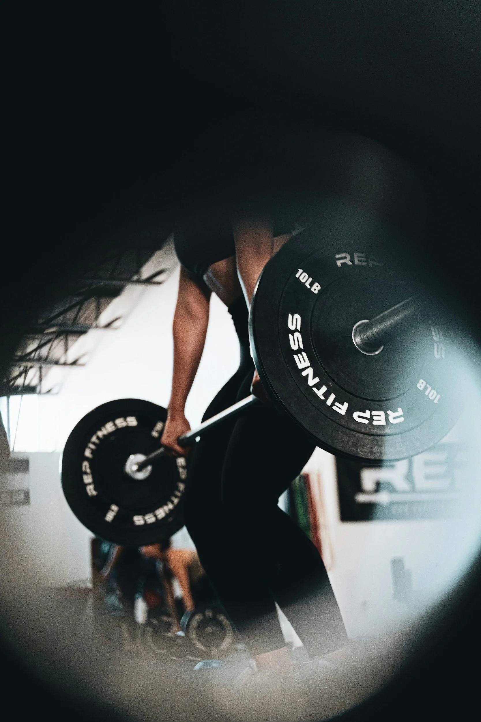 A person lifting a barbell with weight plates in a gym.