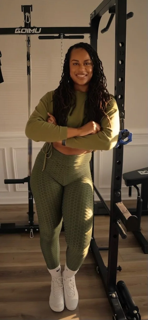 A woman in athletic clothes standing with her arms crossed in front of a gym power rack.