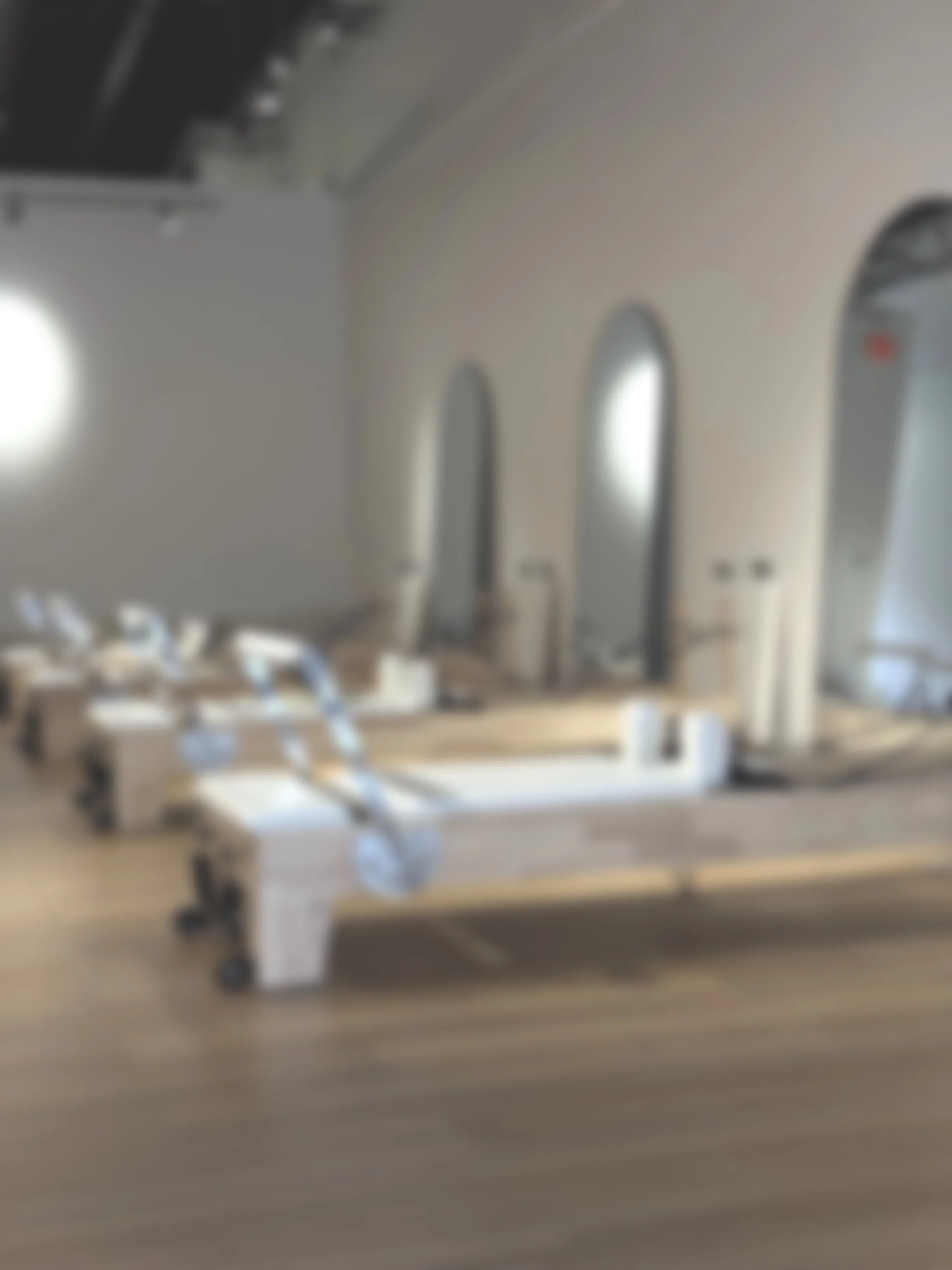 The image shows a room with wooden flooring and a pilates reformer.