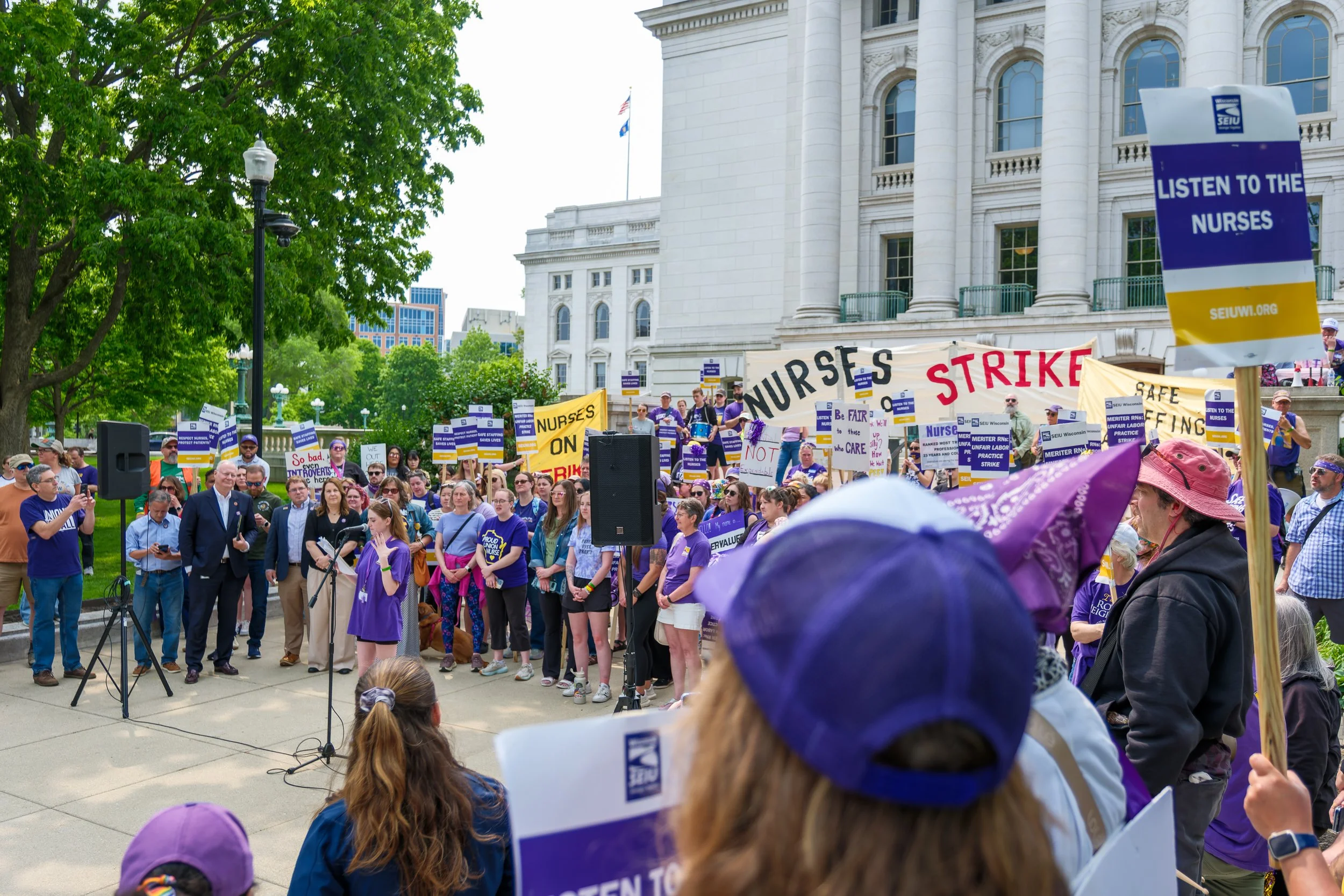 SEIU nurses protest against nurse staffing shortages outside the Wisconsin State Capitol, with people holding signs and banners, some reading 'Nurses on Strike' and 'Listen to the Nurses'.