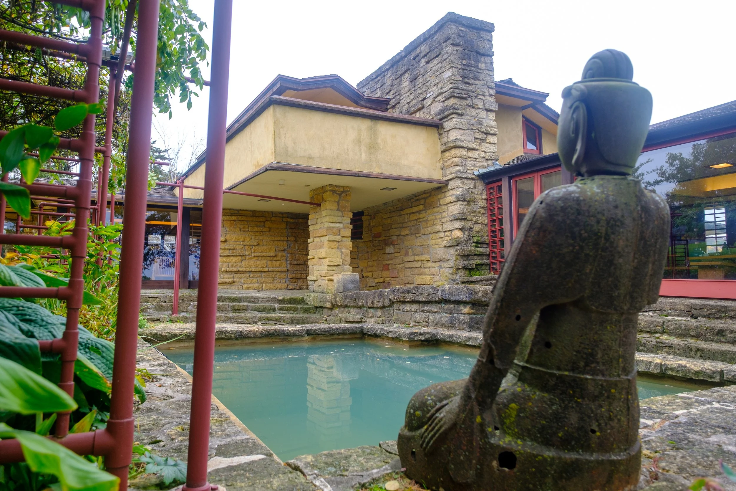 View of a backyard with a small pond and a stone statue of a person at Frank Lloyd Wright's Taliesin near Spring Green, Wisconsin.