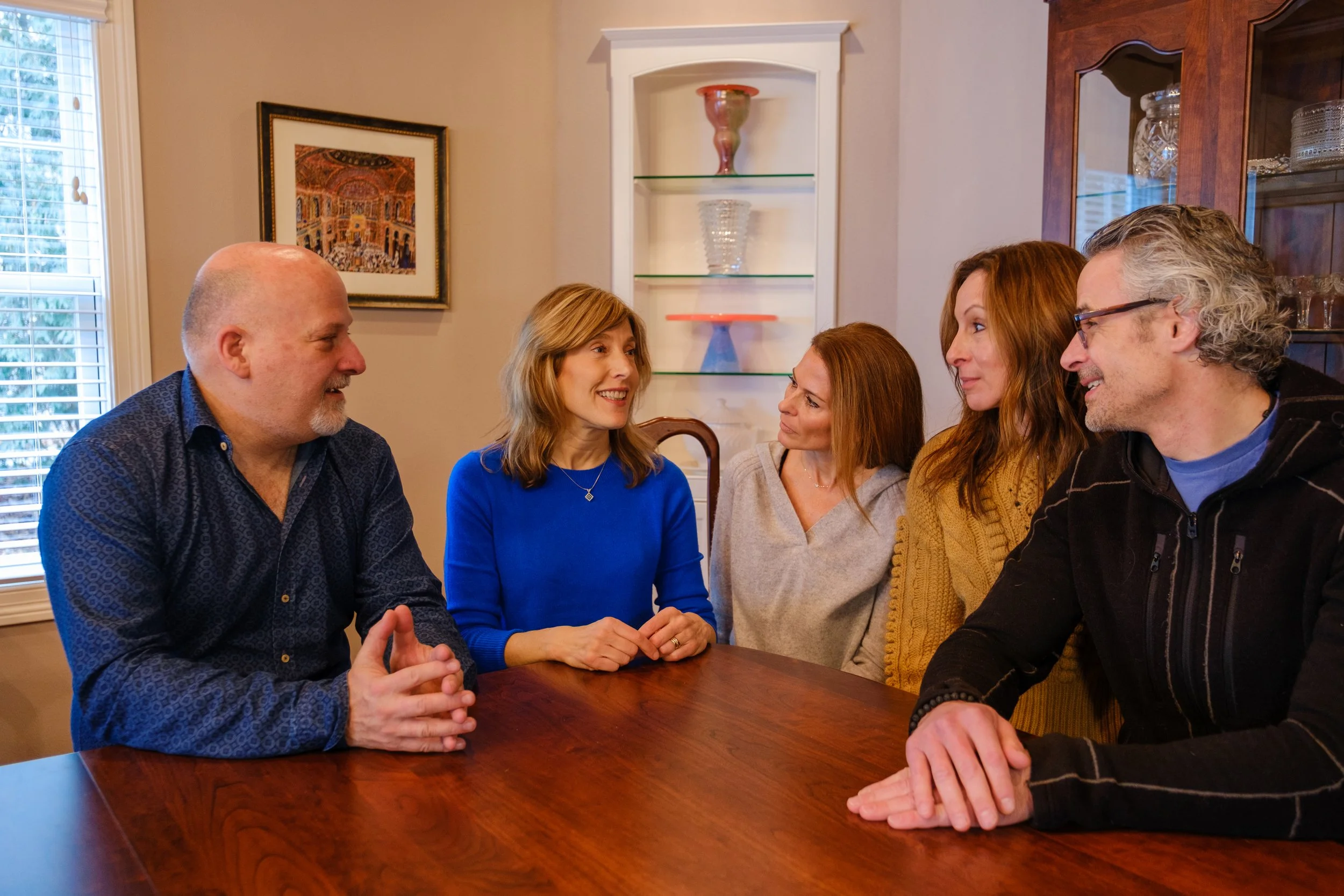Wisconsin State Senator Jodi Habush Sinykin engages in conversation with constituents inside a home, with a window and framed artwork in the background.