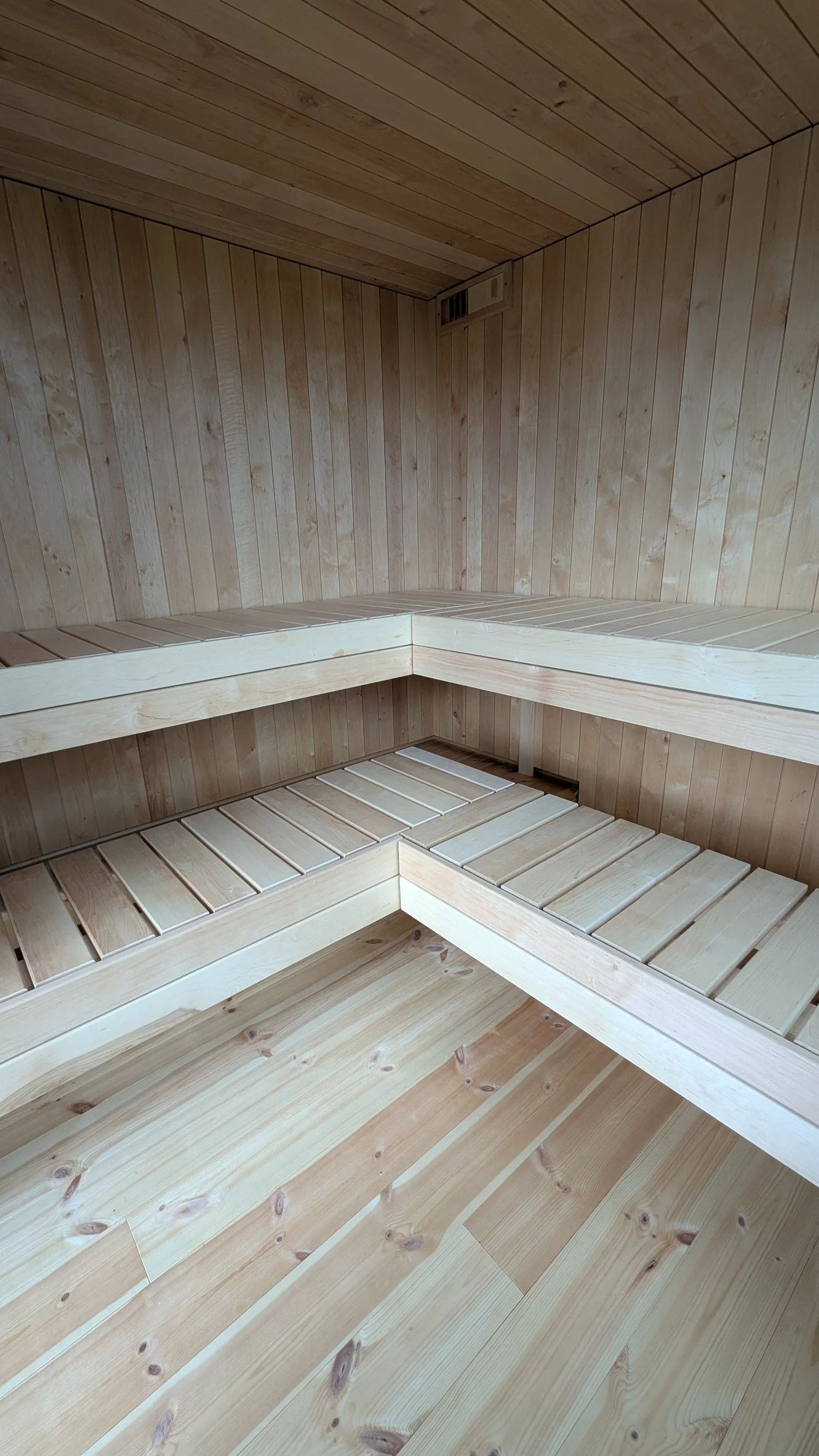 Innvendig i en trebadstue med trebordseter og gulv.