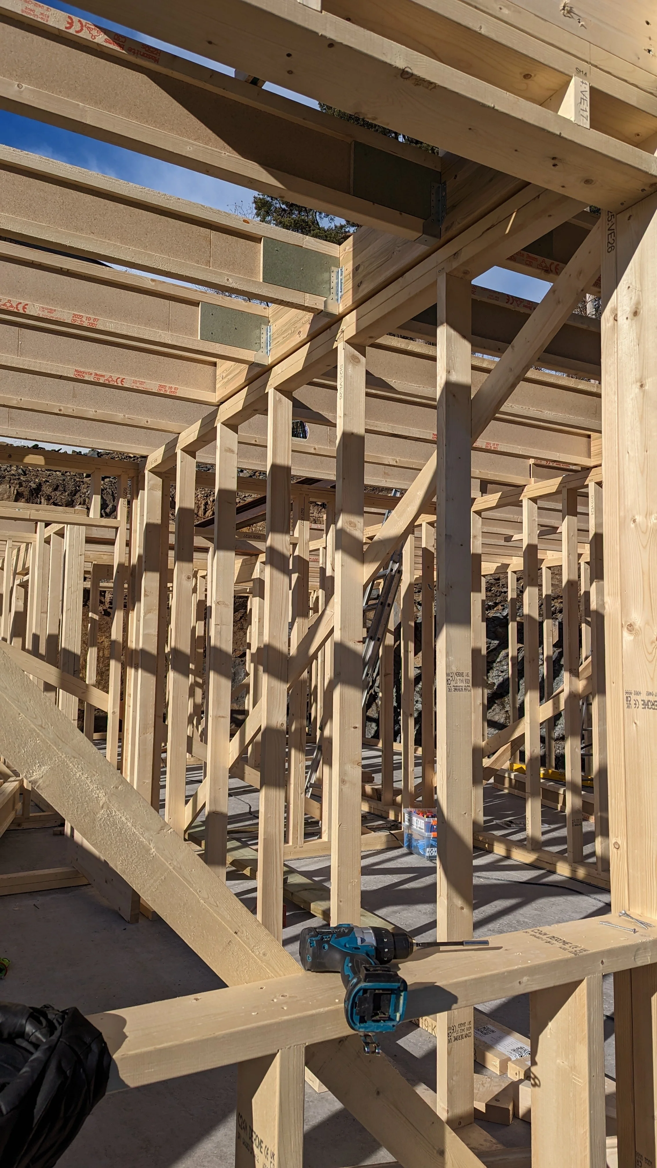 Byggematerialer og trevirke til et hus under konstruksjon. Rå byggeplass med trestender og verktøy.