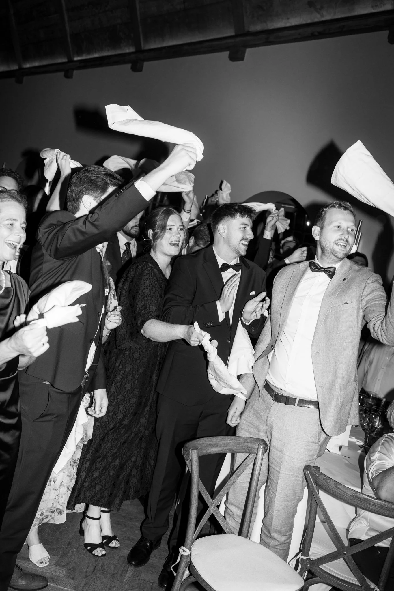 Menschen feiern bei einer Party, einige werfen Stoffservietten in die Luft, einige lachen und applaudieren.