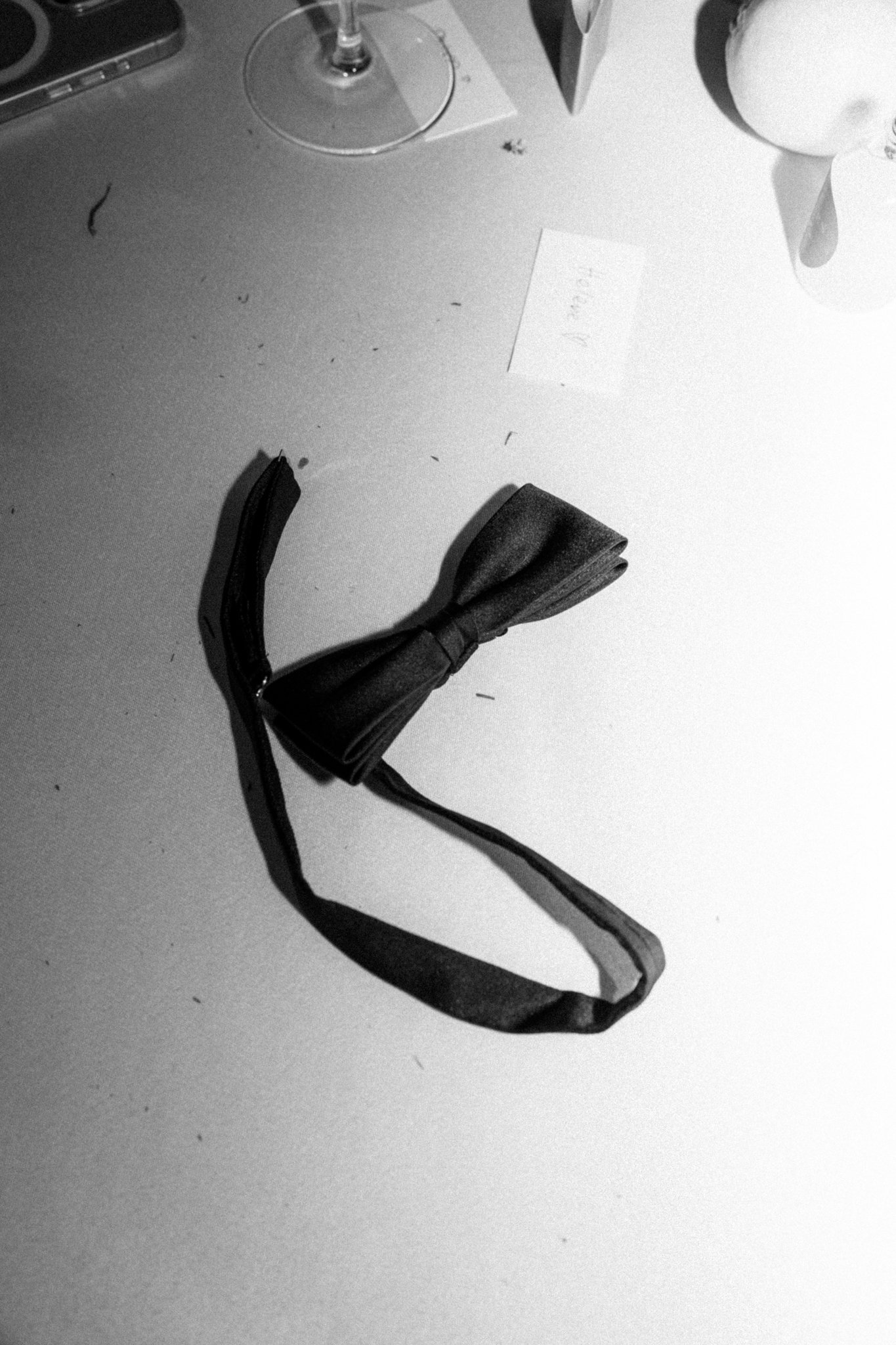 Schwarz-weiß-Bild eines auf einem Tisch liegenden schwarzen Fliegenbands.