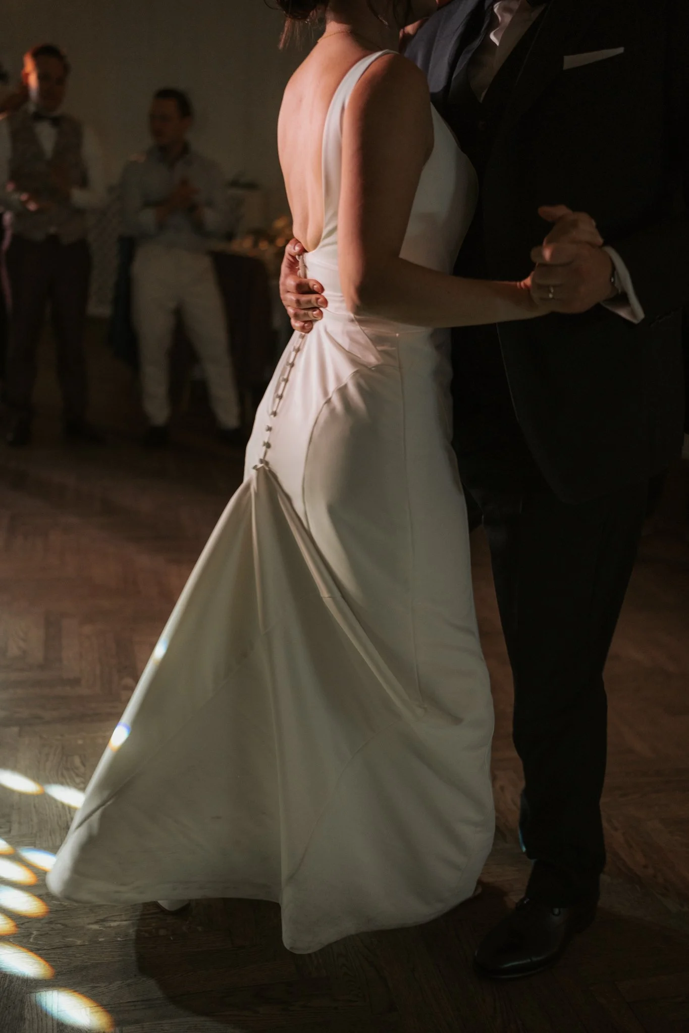 Ein Brautpaar tanzt bei einer Hochzeit. Die Frau trägt ein weißes Brautkleid, der Mann einen schwarzen Anzug.