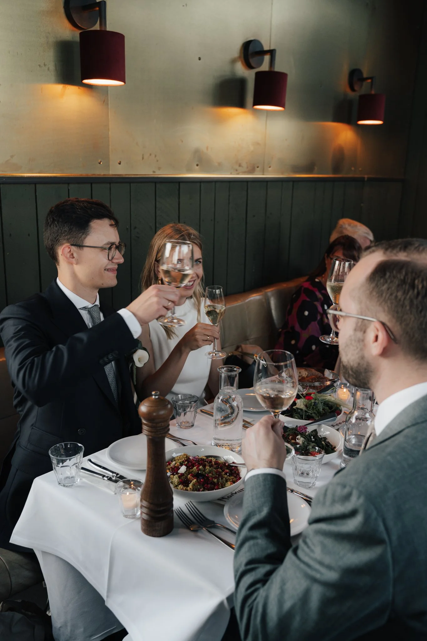 Menschen beim festlichen Essen in einem Restaurant, sie stoßen mit Gläsern Wein an.