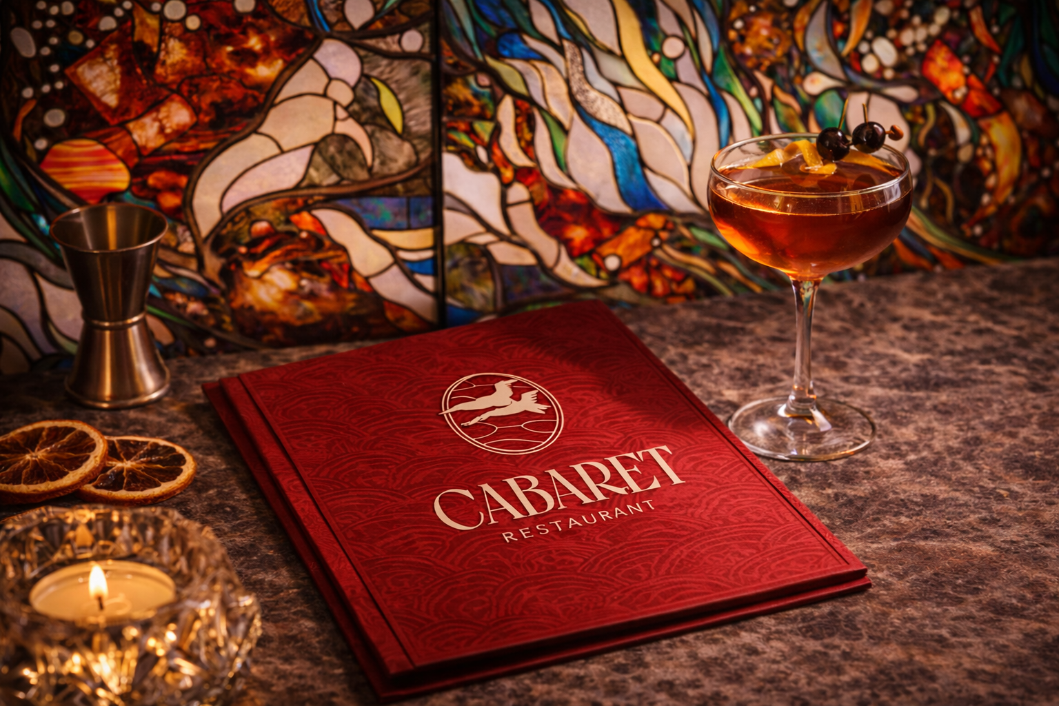 Une carte du restaurant Cabaret posée sur un comptoir en pierre, avec un cocktail de rouge, une petite cheminée décorative, des tranches d'orange séchée, et un fond coloré et lumineux dans un style artistique.