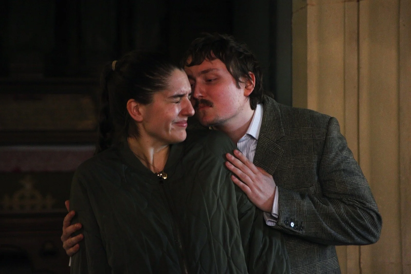 A woman crying while being comforted by a man who is touching her shoulder