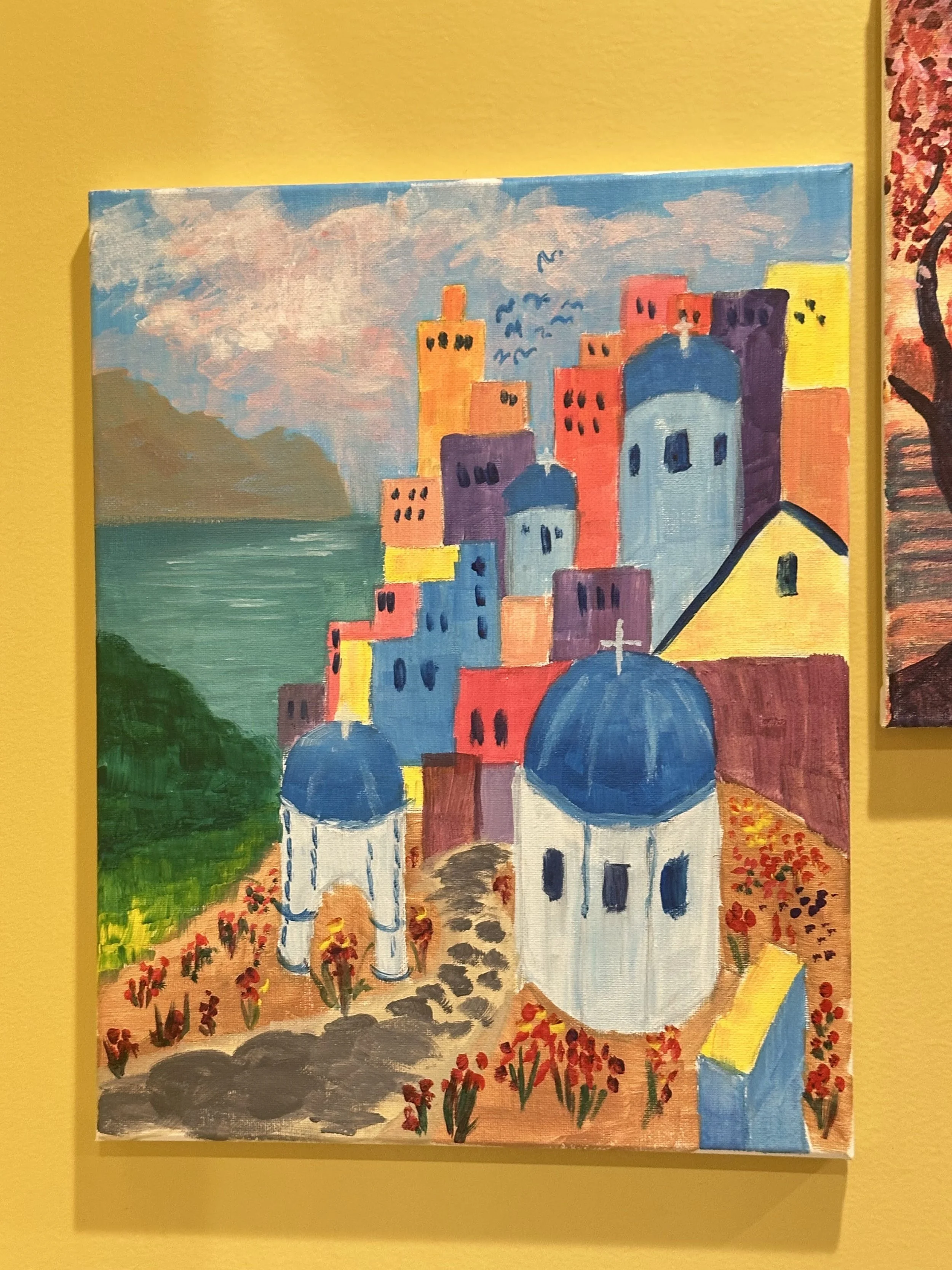 Colorful painting of a Greek village with white churches and blue domes, surrounded by colorful buildings, set against a landscape with mountains and water.