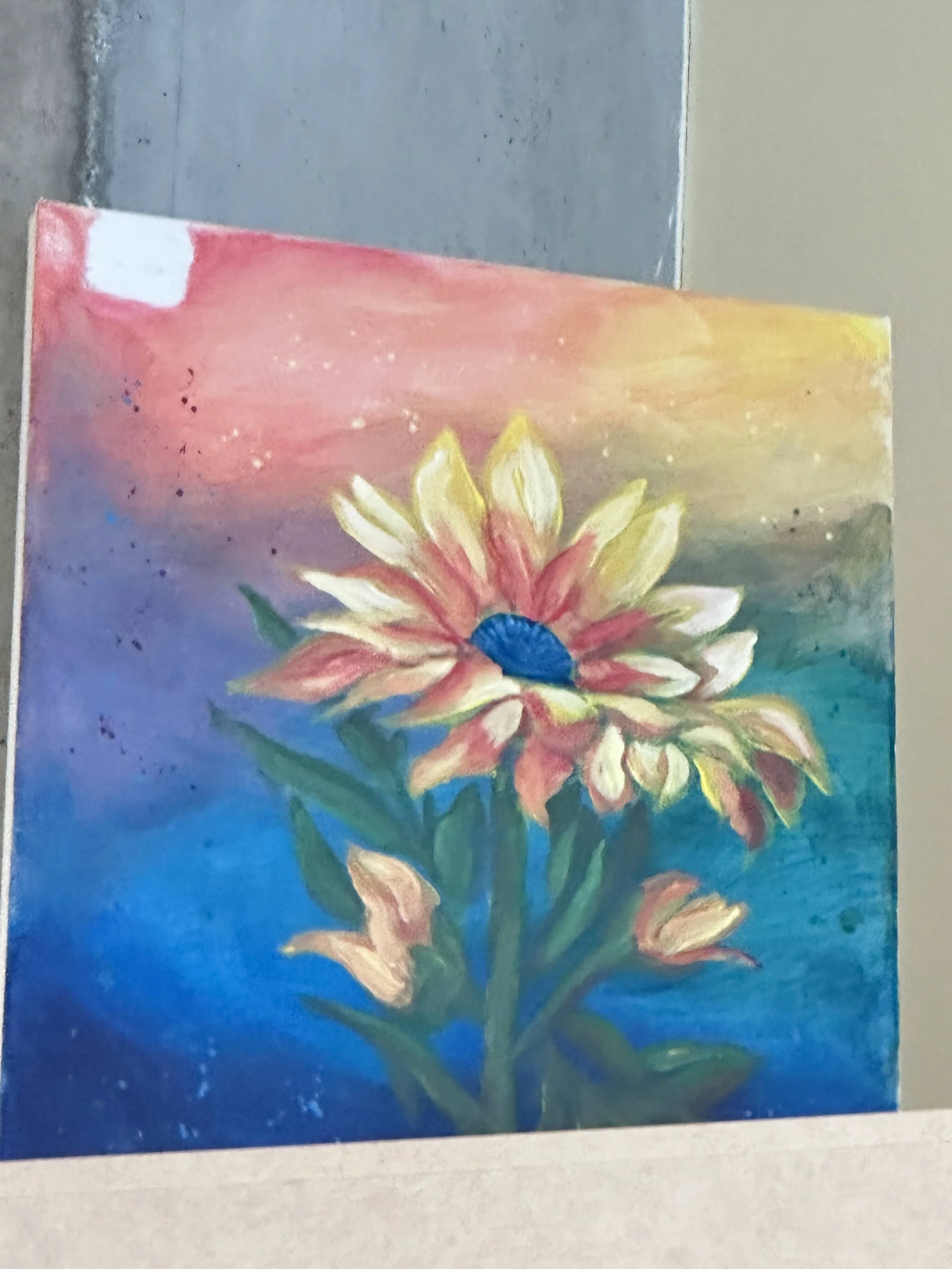 A colorful acrylic painting of a flower with white petals and a dark blue center against a gradient background of pink, yellow, green, and blue.