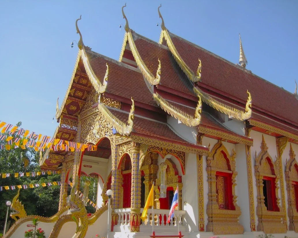 Traditional Thai temple with ornate gold detail and multi-tiered roof with decorative finials