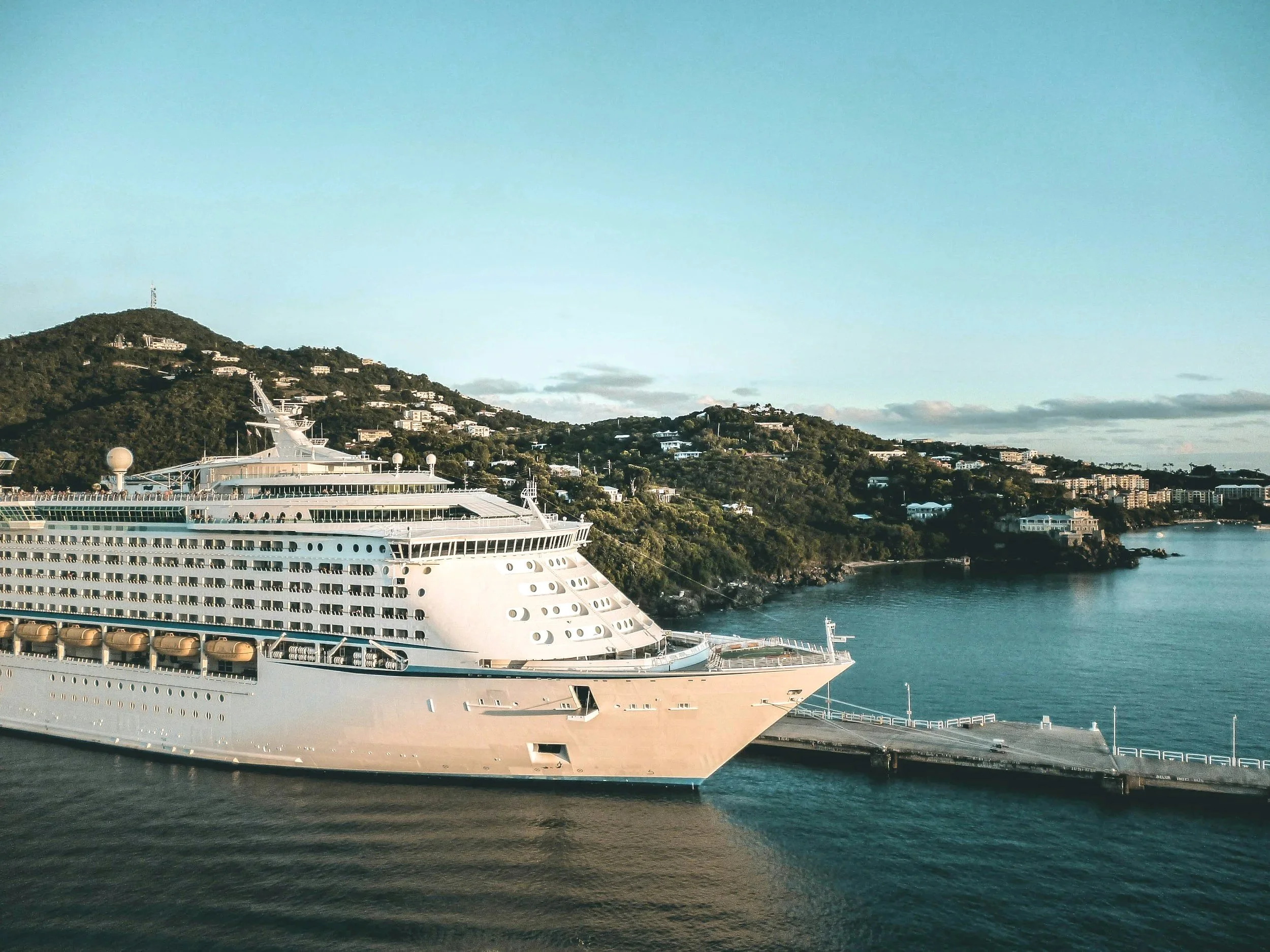 Large white cruise ship docked at a harbor in the Mediterranean.