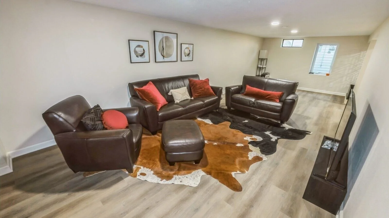 Basement living room with leather lounging area.  2 queen beds opposite ends of room.