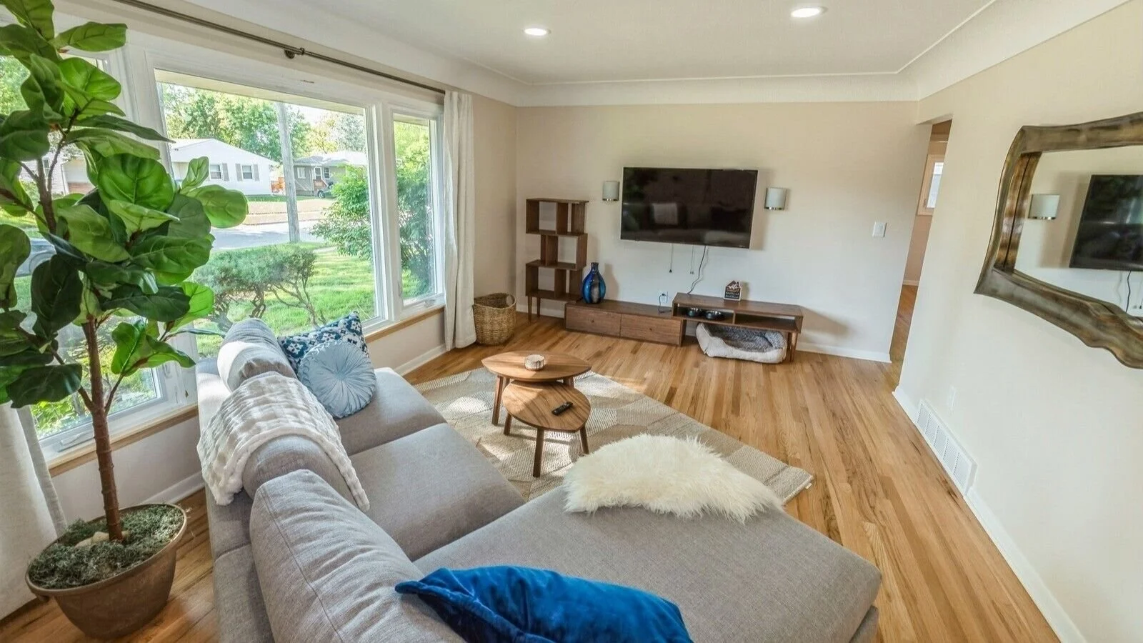 Spacious living room with big screen smart TV. Large bay windows and natural light.