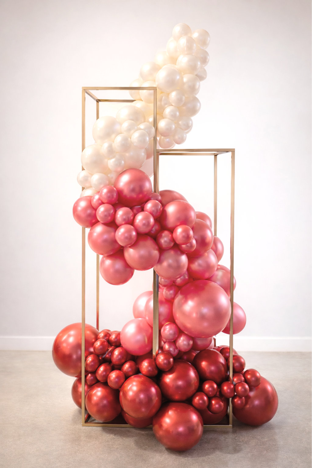 A modern sculpture composed of pink and white balloons inside a metallic geometric frame.
