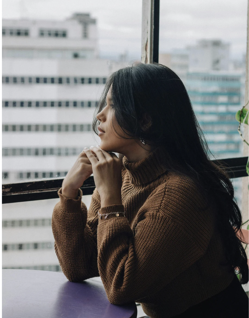 dark haired woman staring out window.