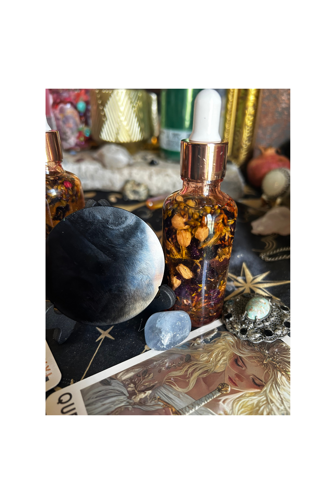 Collection of crystals, gemstones, and a bottle filled with dried flowers on a tarot card table.