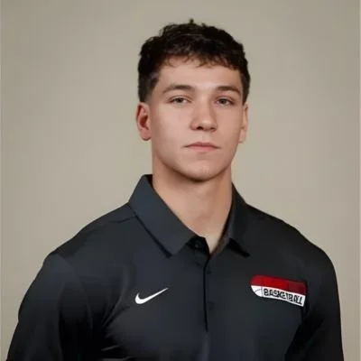Young man wearing a black Nike basketball polo shirt, looking at the camera, against a plain light background.