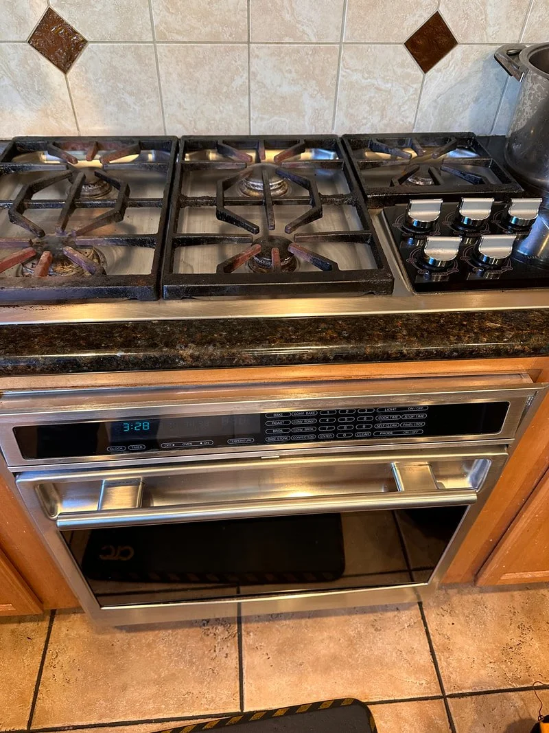 A kitchen stove with three burner gas cooktop and a digital oven with control panel, located in a kitchen with tiled backsplash.