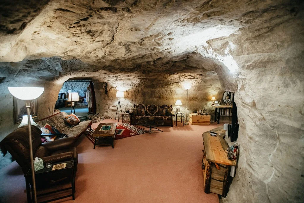 Living room inside a cave with sofas, lamps, and a coffee table.