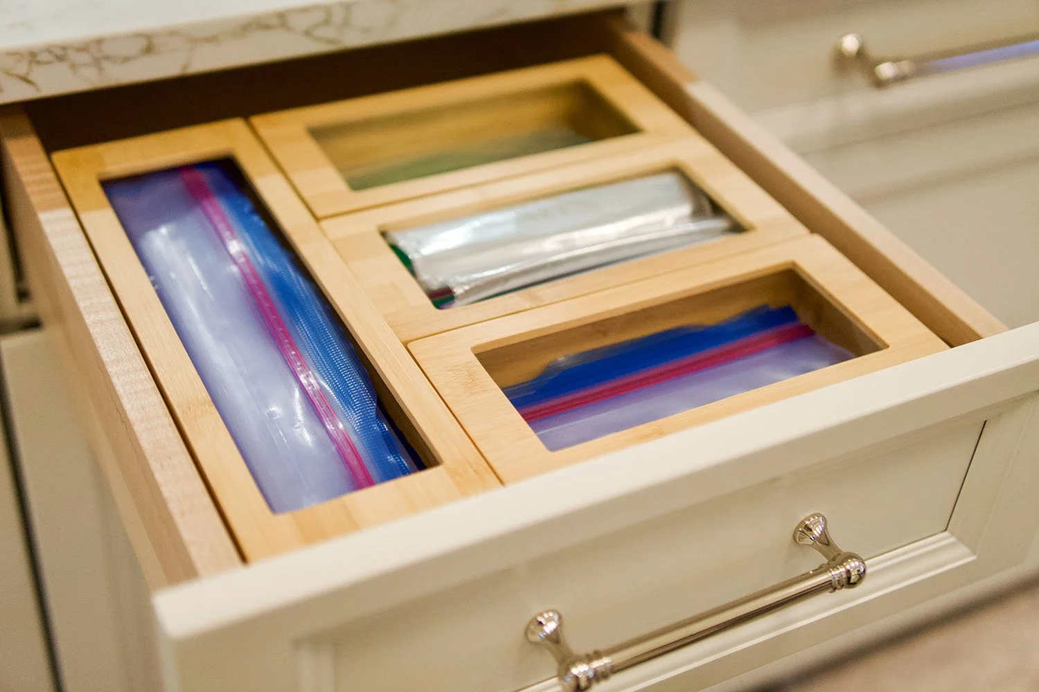 Drawer with labeled plastic zipper bags used for organizing small items, with a drawer knob visible at the bottom.