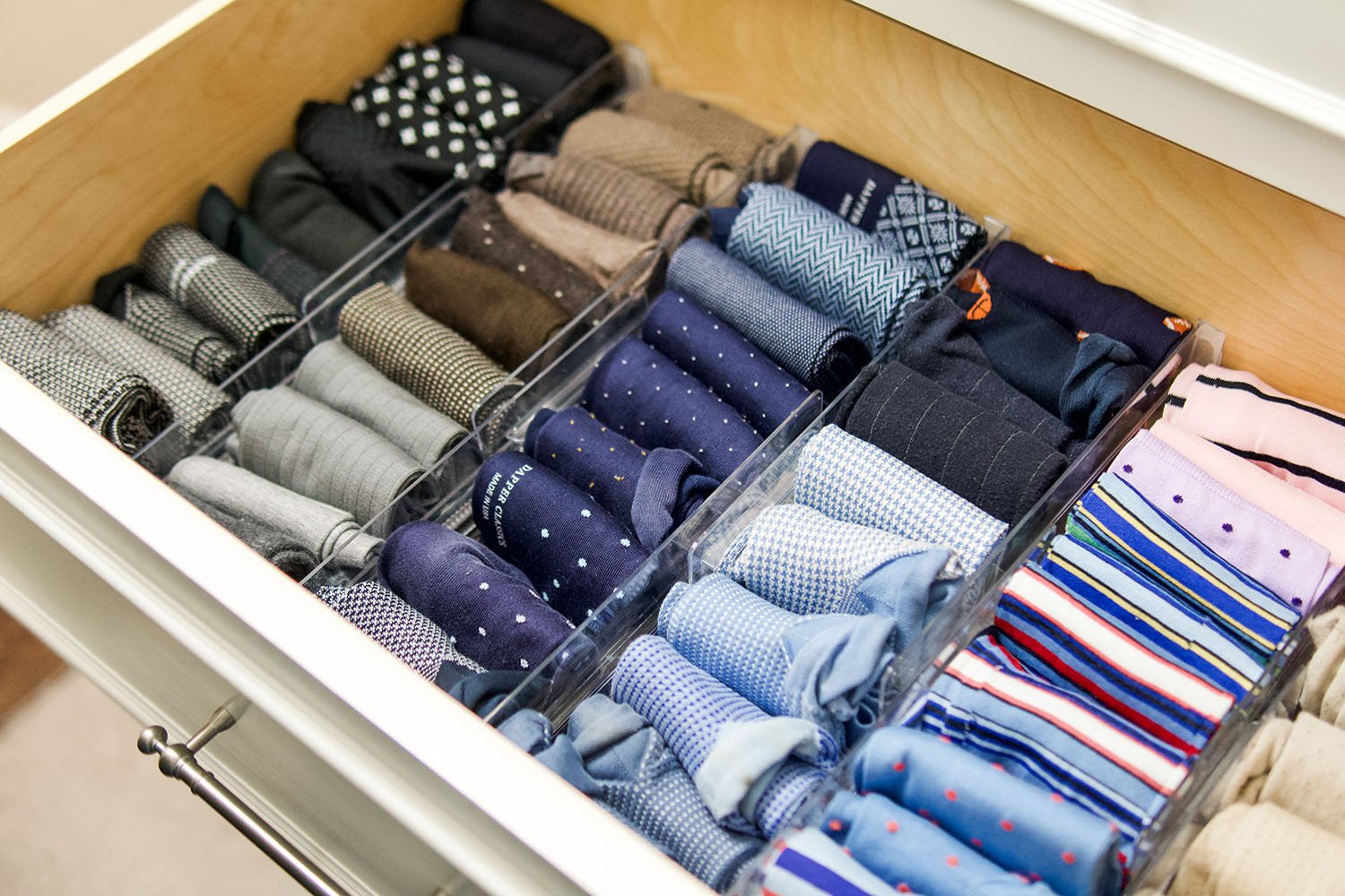 Drawer containing neatly organized men's socks in various patterns and colors.