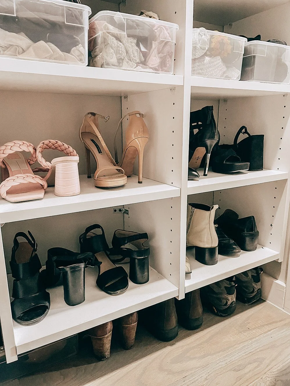 A shoe closet with multiple pairs of high heels, boots, and shoes organized on white shelves.