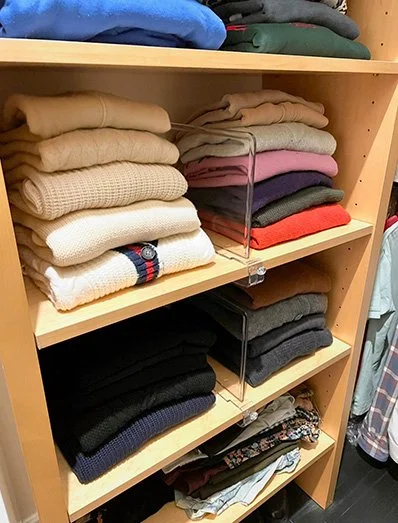 Shelf with folded sweaters and shirts in various colors and patterns.