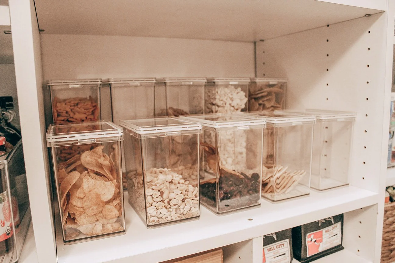 Clear plastic containers filled with various dried ingredients on a white shelf in a store.