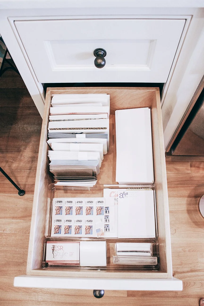 Drawer containing various sheets of paper, stamps, and office supplies.