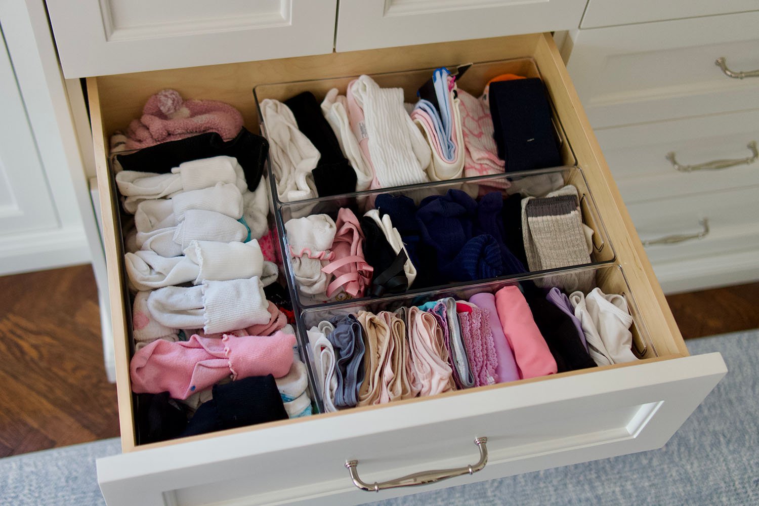 Open drawer containing neatly folded socks, underwear, and hair accessories organized in clear dividers.
