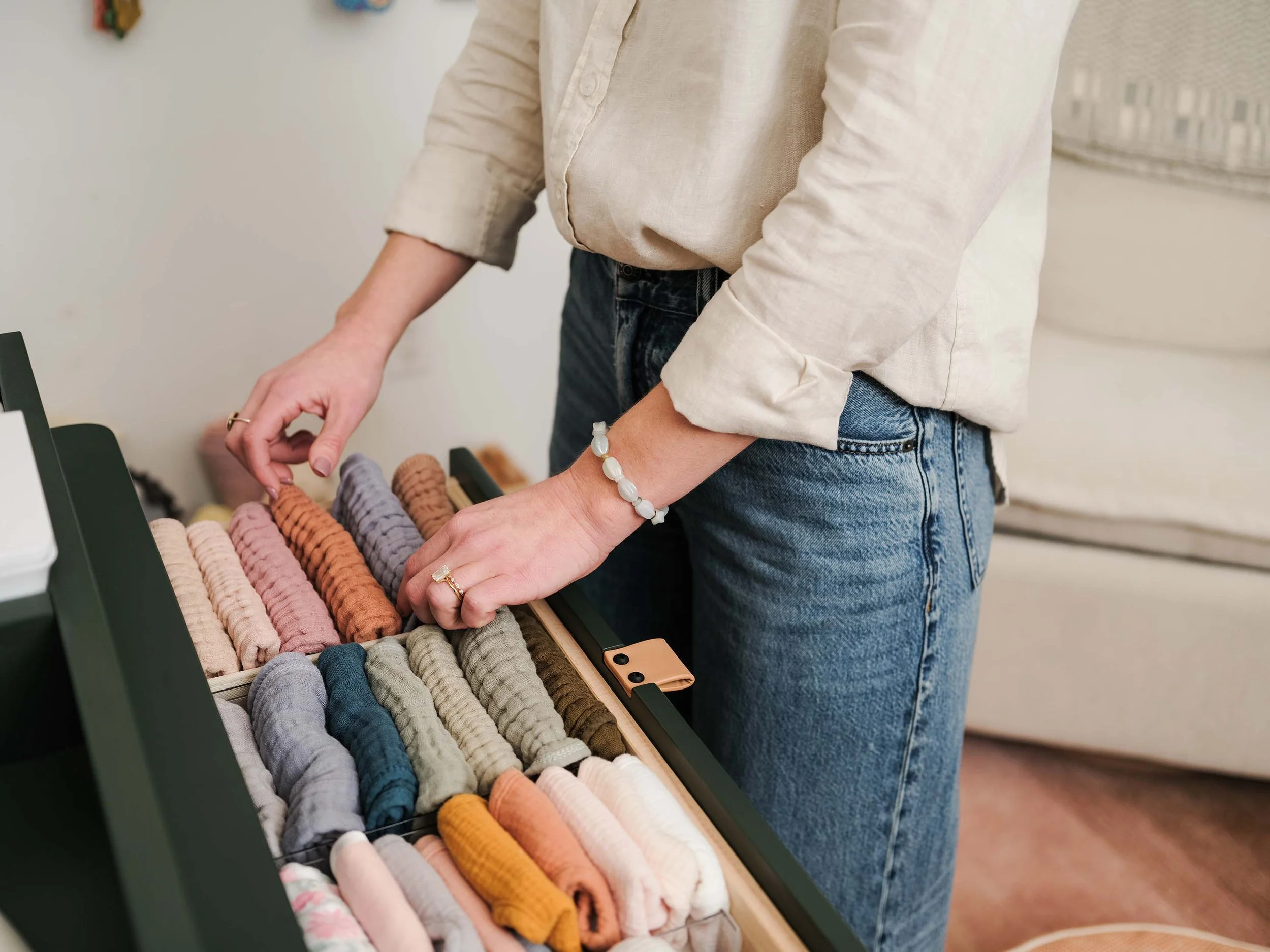 Person browsing through a selection of colorful knitted scarves displayed on a rack.
