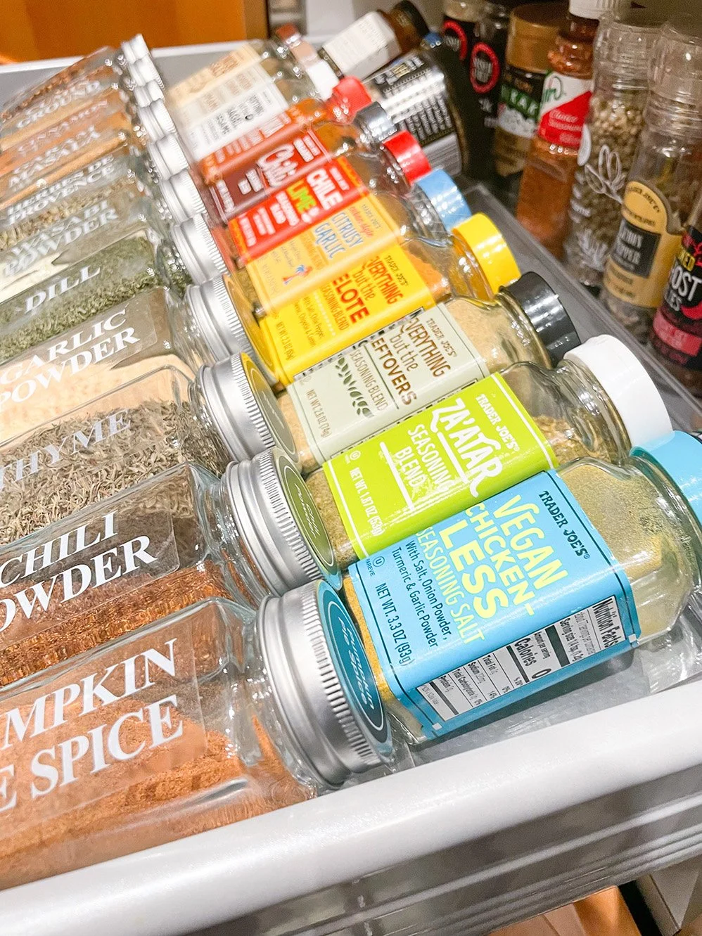 Assorted spices in glass jars with metal lids, including garlic powder, chili powder, pumpkin pie spice, turmeric, cumin, and sea salt, on a kitchen shelf.