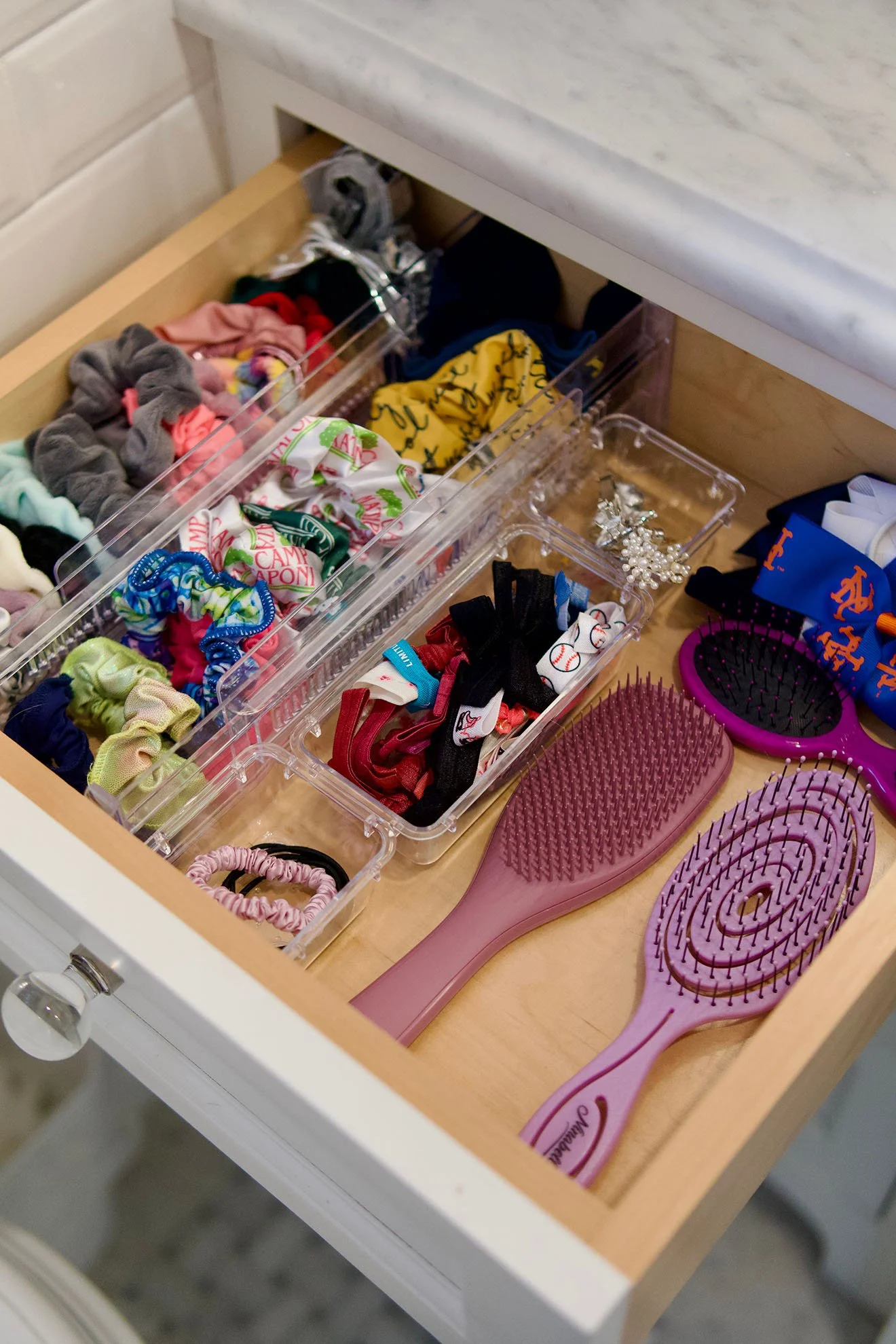 Drawers containing colorful scrunchies, headbands, and hairbrushes.
