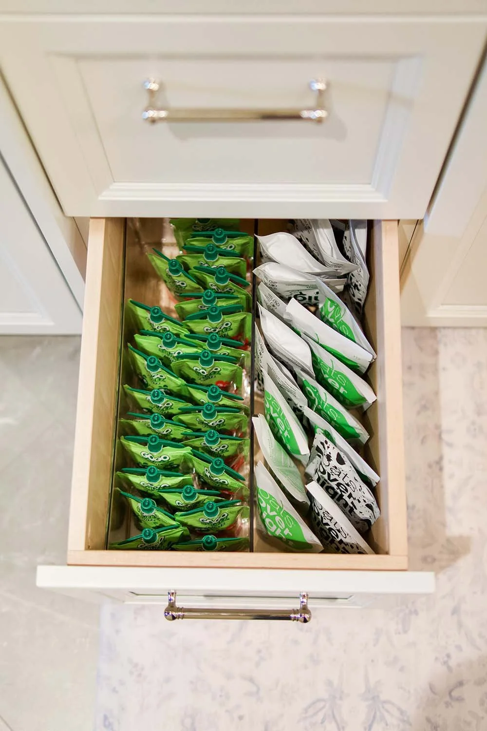 Drawers with green and white snack packages organized side by side.