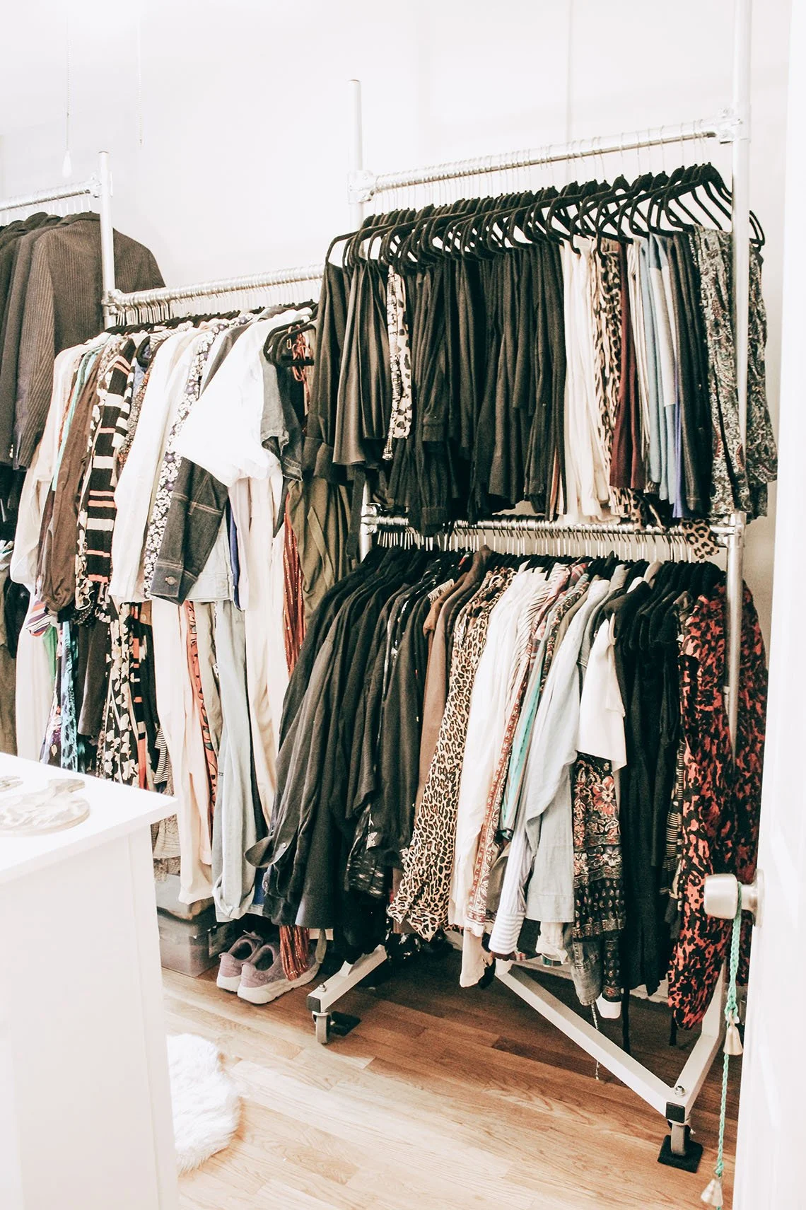 Clothing rack with various shirts, pants, and leggings in a retail store or closet.