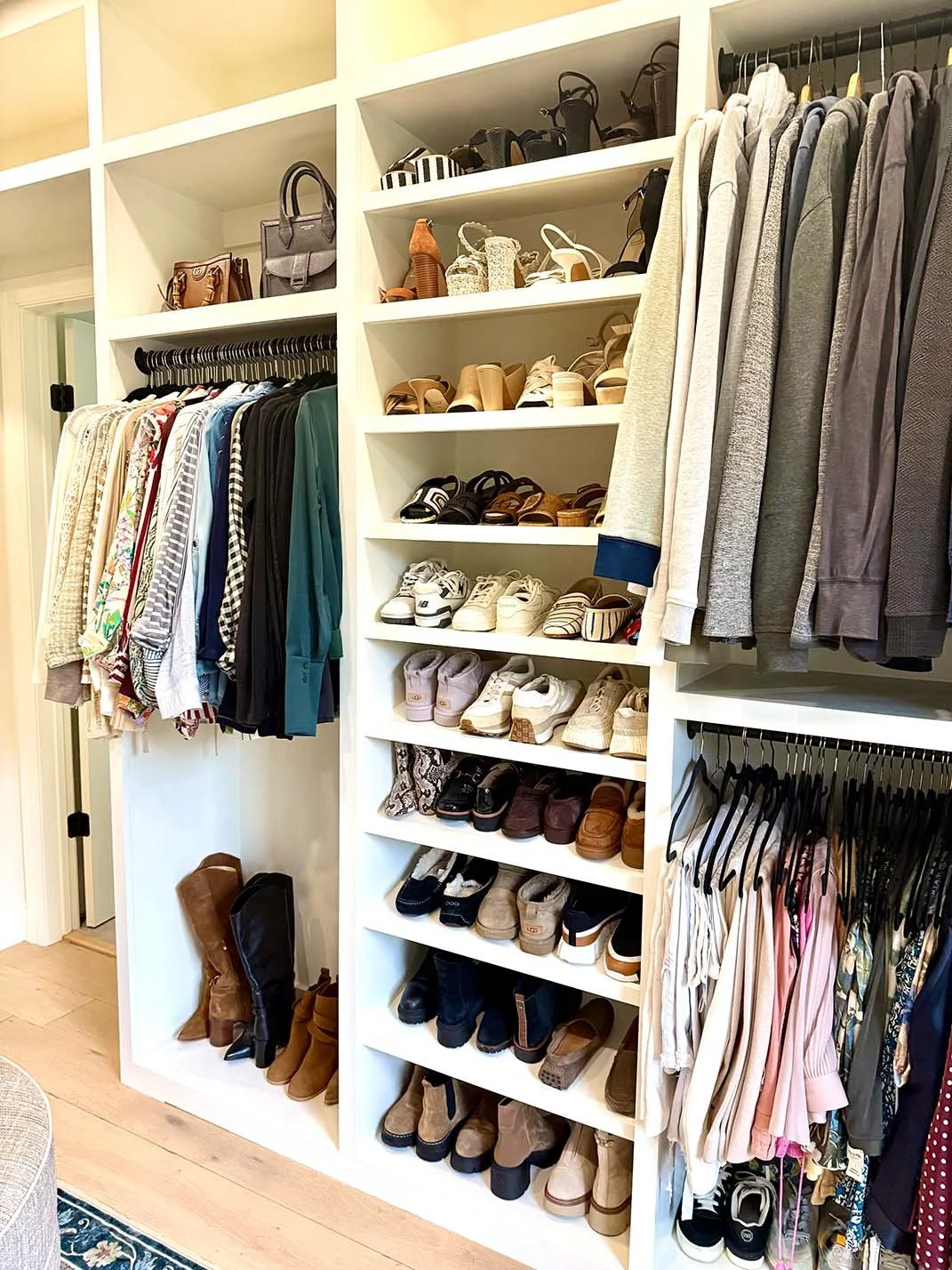Clothing closet with shoes, handbags, and apparel organized on shelves and hanging racks.