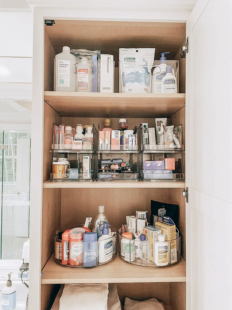 Medicine cabinet with various medications, supplements, and personal care products organized in clear containers.