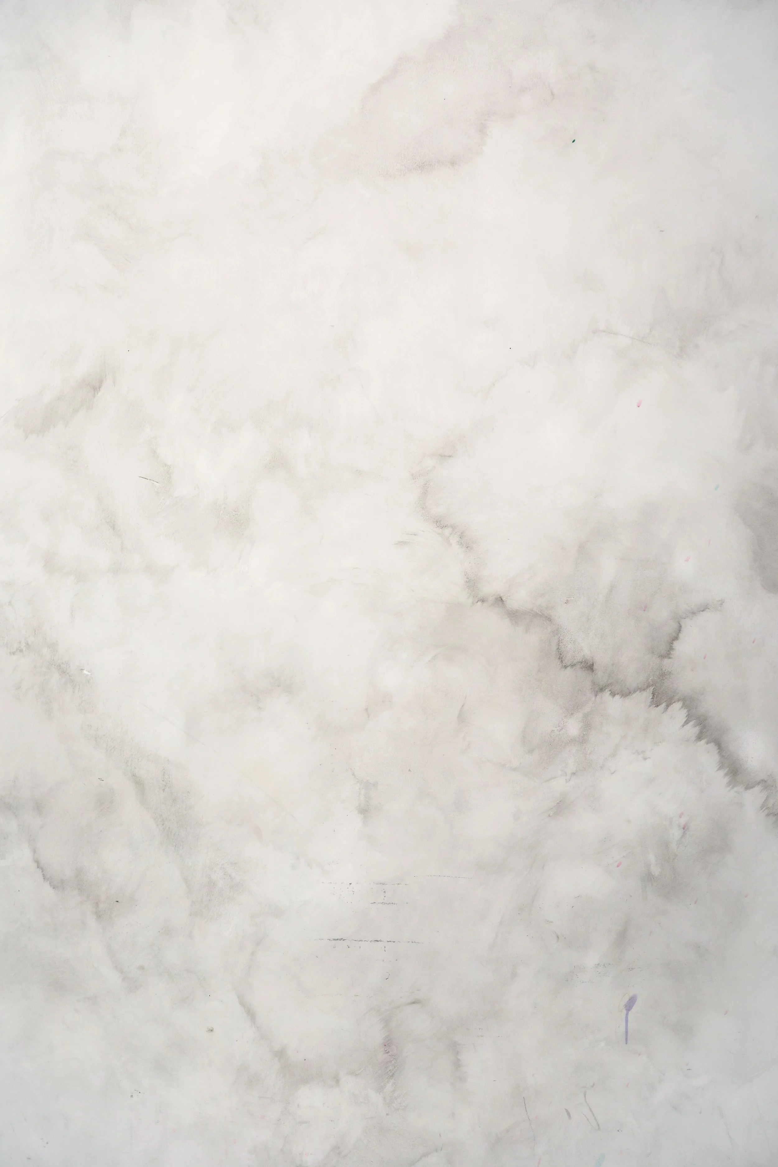 A white wall with grey and black marbled streaks and some faint marks and spots.