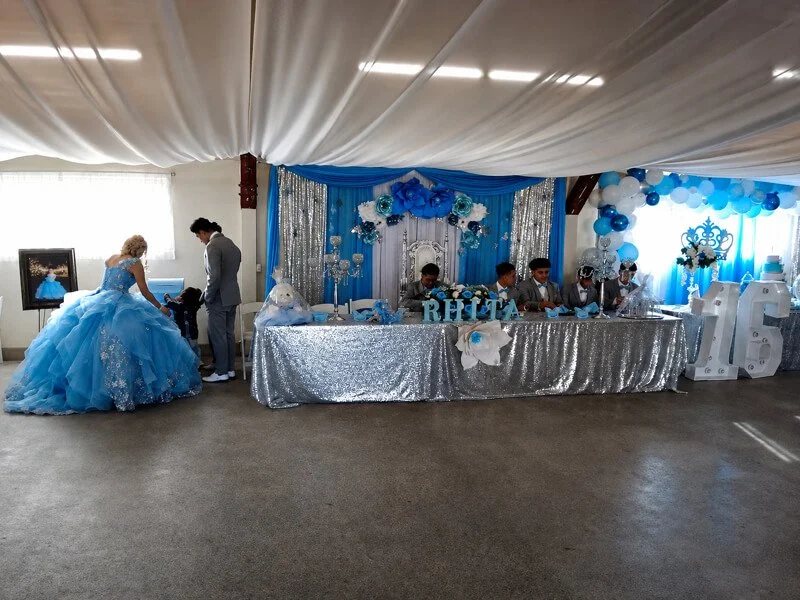 Back Hall quinceañera setup at the FDES Portuguese Hall of Monterey with decorated head table and blue décor.
